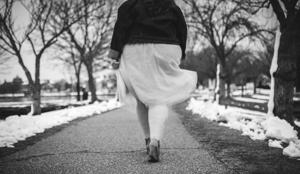 black and white photo of bettye walking away from camera in swishy tulle skirt