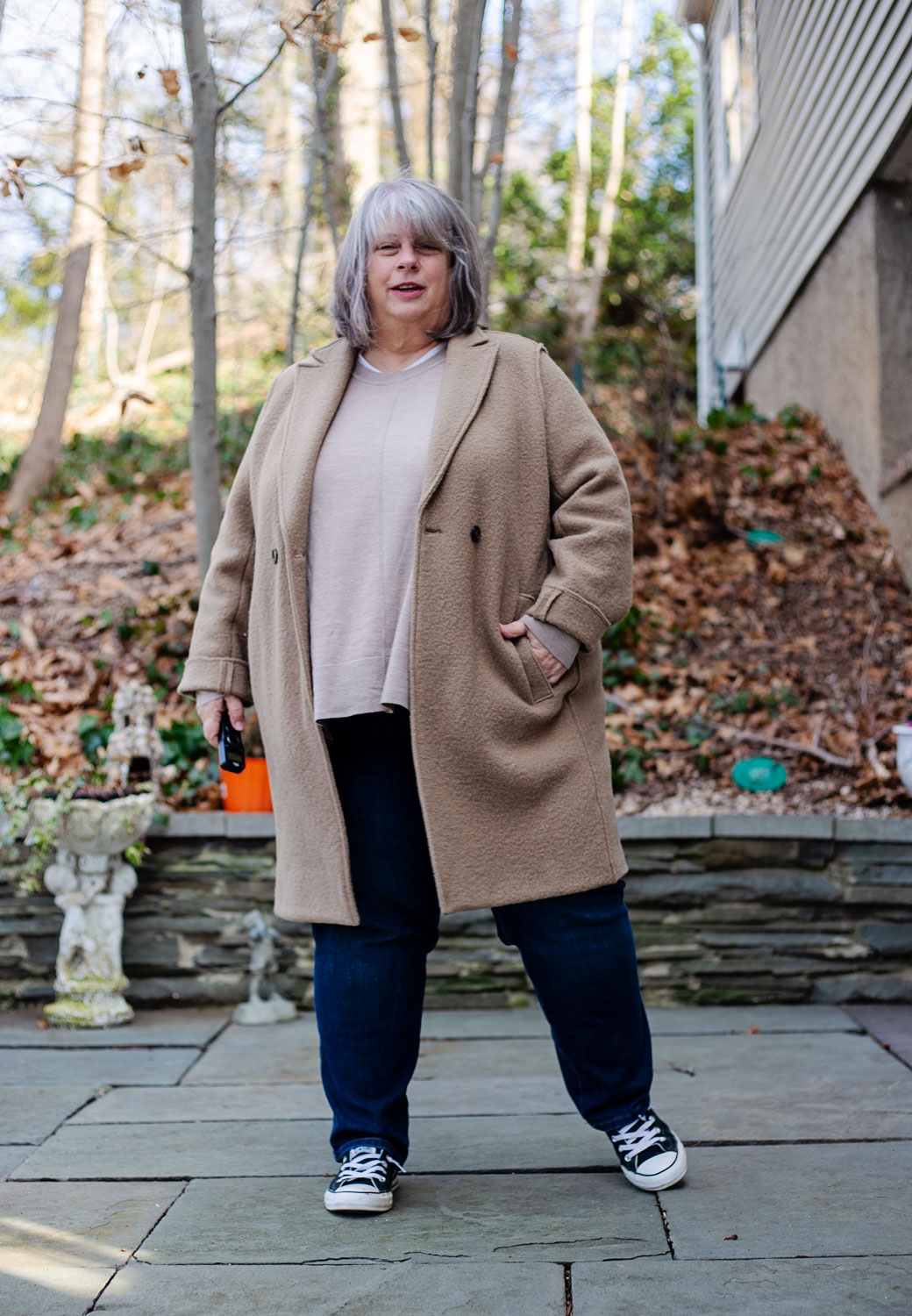 bettye standing on patio in taupe sweater and camel coat