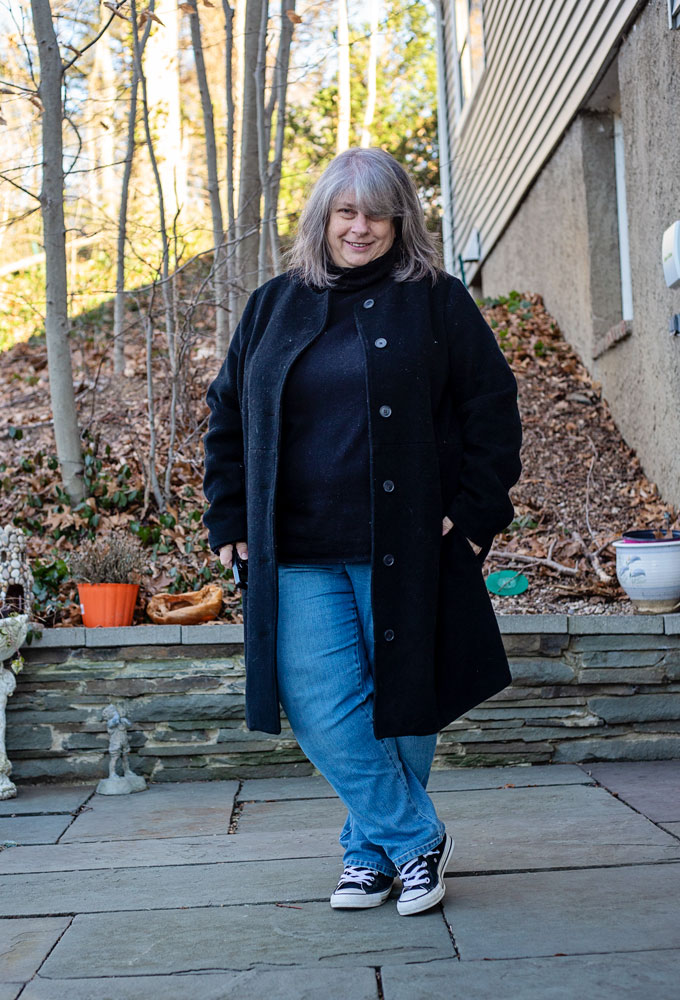 bettye standing on patio in dark sweater and coat