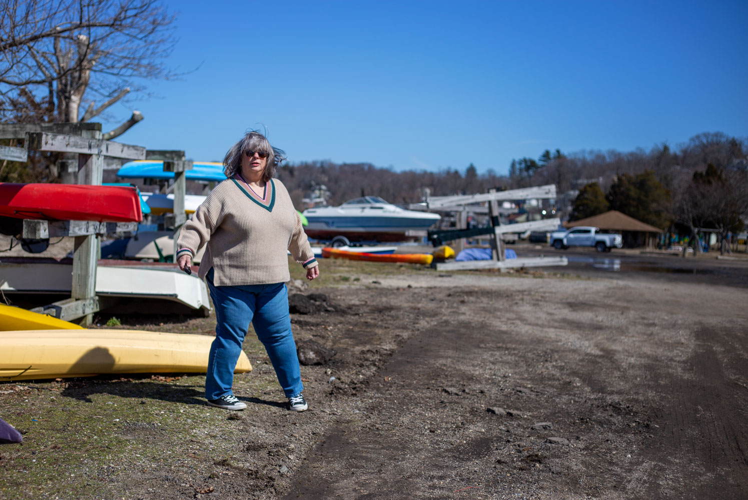 Bettye standing awkwardly near the kayak racks at the beach by the harbor