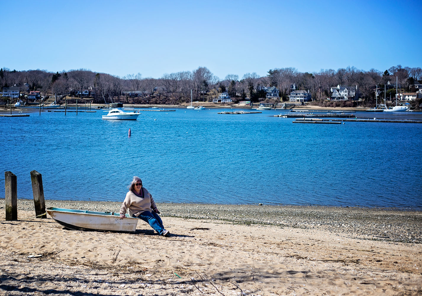 bettye sitting on a small boat on the beach by the harbor