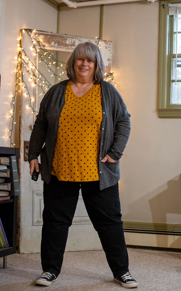 bettye stnading in lustard gold polka dot tee shirt in front of antique door with twinkle lights